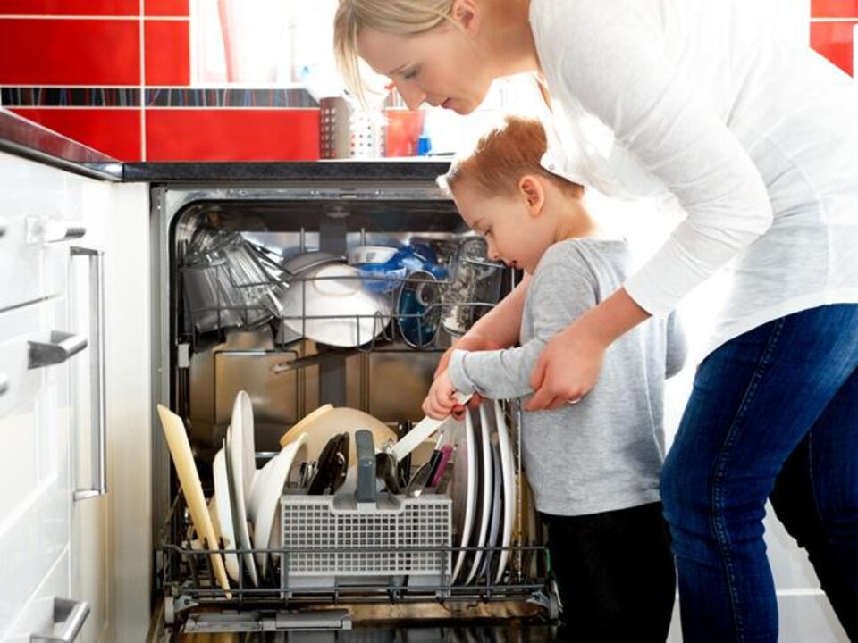 Une mère et son jeune enfant remplissent le lave-vaisselle.
