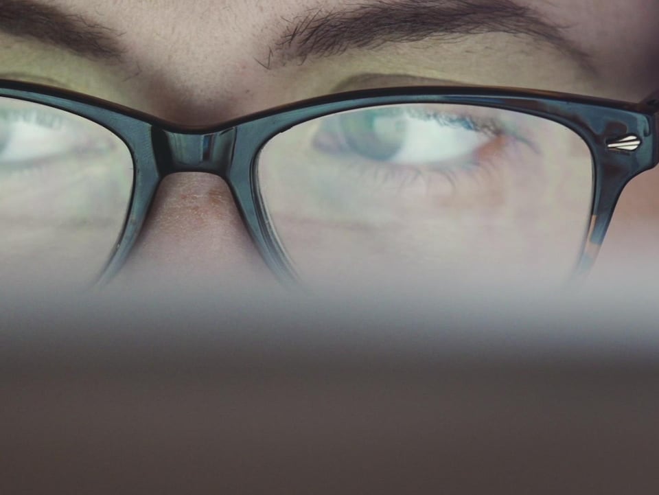 Une personne portant des lunettes regarde un écran.