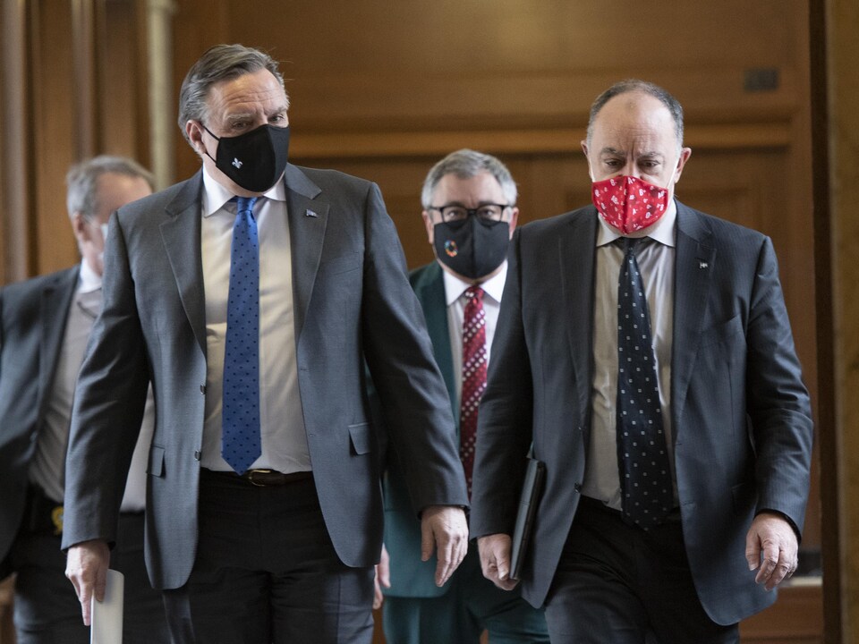 François Legault, Christian Dubé et Horacio Arruda marchent dans un corridor.