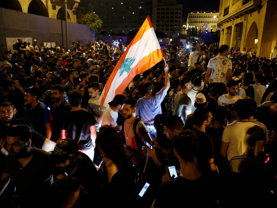 Des manifestants dans la nuit brandissent un drapeau.