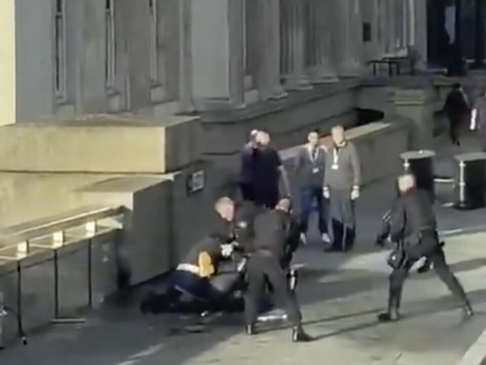 Un homme est étendu et maintenu au sol par des policiers armés.