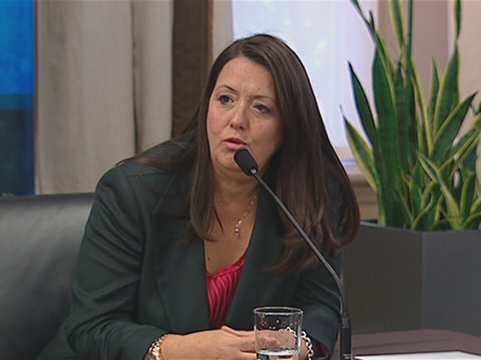 Une femme parle dans un micro, assise derrière une table.