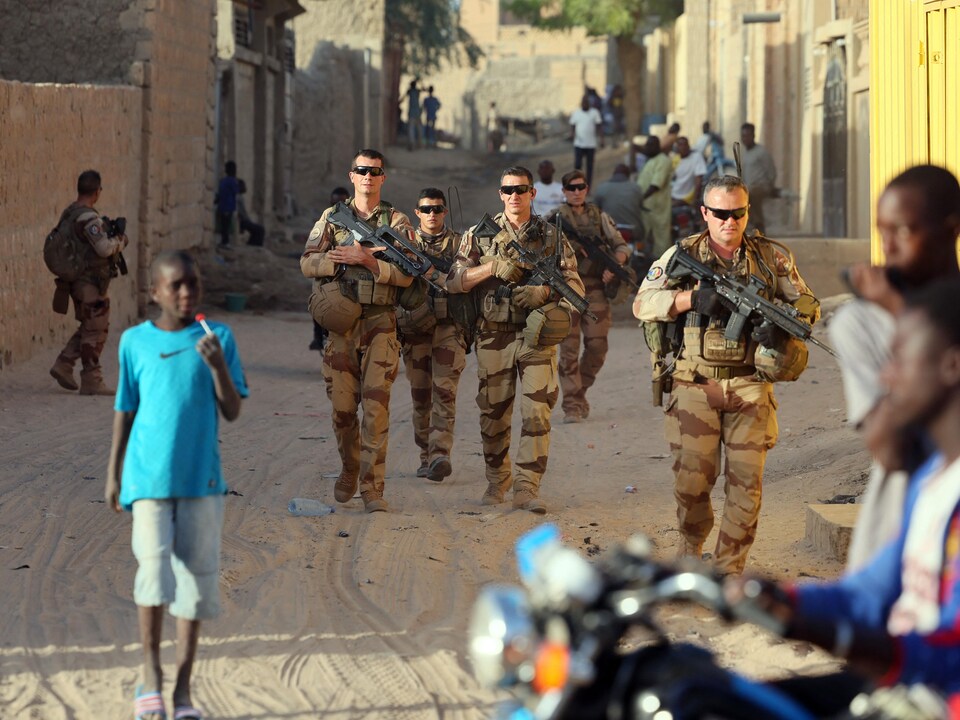 Des soldats français armés marchent entre les passants.