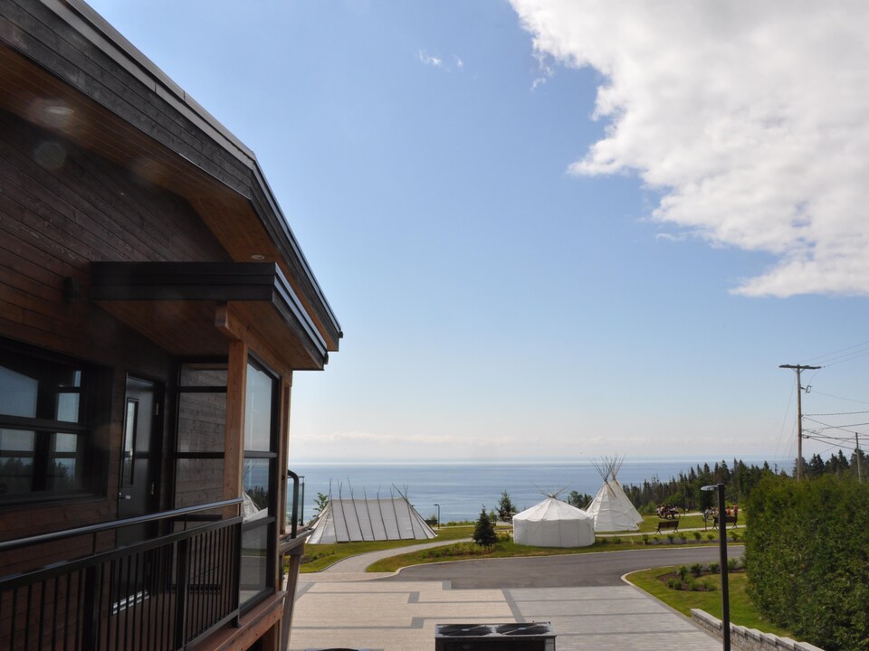 Un bâtiment en bois et des tentes traditionnelles surplombent le fleuve.