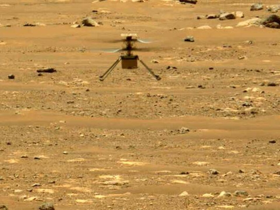 L'hélicoptère vole au-dessus de la surface martienne.