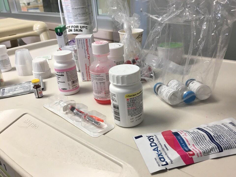 Des bouteilles de médicaments et des seringues sur une table d'hôpital. 