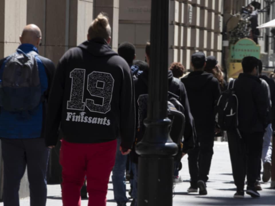 On voit des jeunes, de dos, qui marchent dans une rue du Vieux-Montréal.
