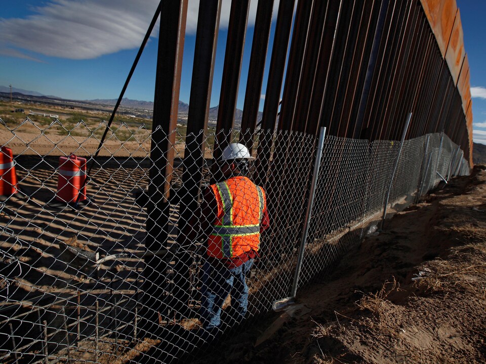 Un homme travaille à la construction d'un mur à la frontière entre les États-Unis et le Mexique.