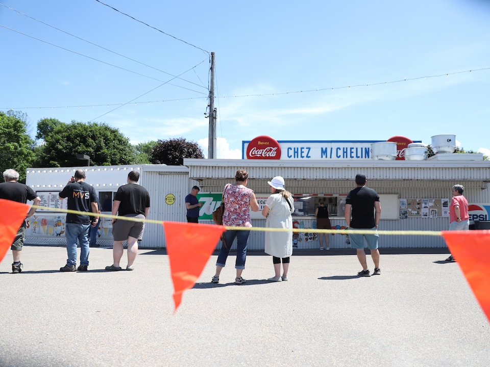 Des gens font la file sur un stationnement devant la cantine « Chez Micheline ».