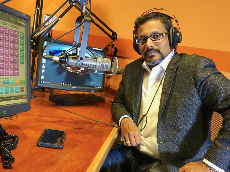 Ghanaharan S. Pillai, animateur d’émissions politiques à la radio et à la télé tamoule est assis dans un studio.