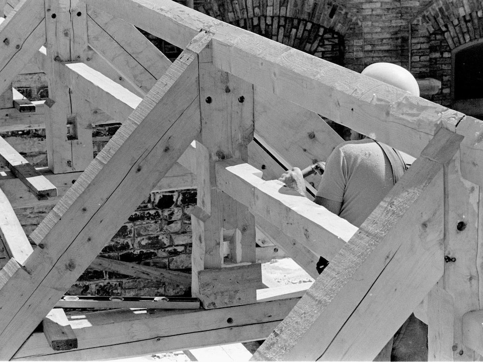 Un ouvrier au travail sur une charpente de bois, sur le chantier de Place-Royale, en août 1971.
