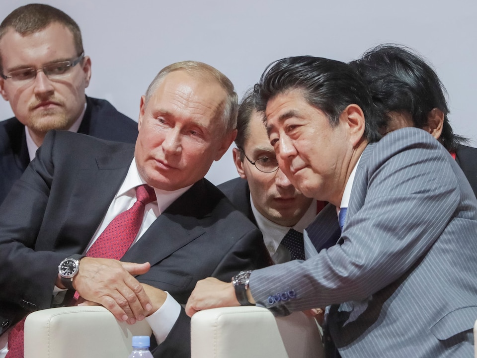 Vladimir Poutine et Shinzo Abe penchés l'un vers l'autre.