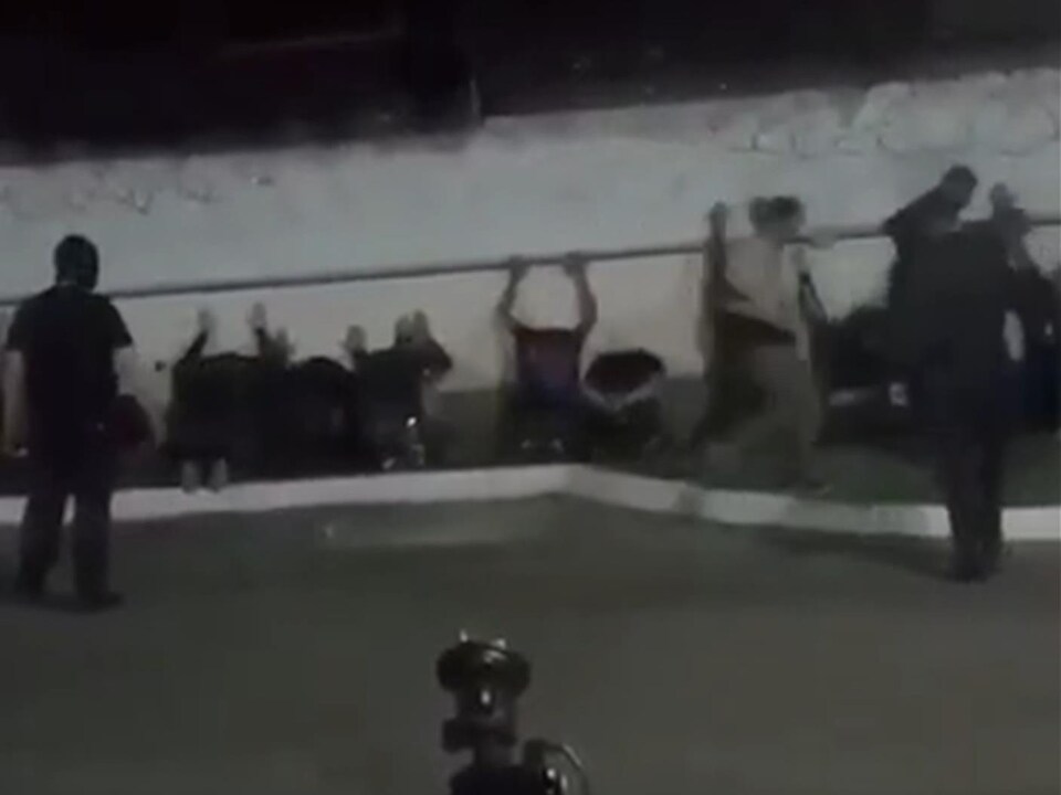 Des hommes alignés le long d'un mur.