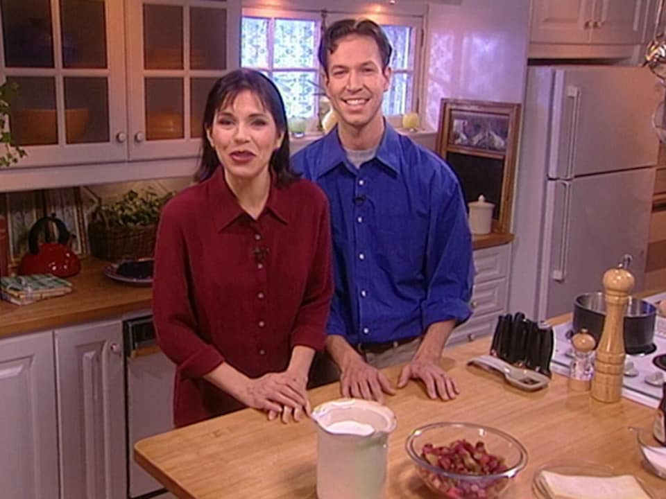 Ricardo Larrivée et Mireille Deyglun, debout dans une cuisine pour présenter une recette de tarte à la rhubarbe.