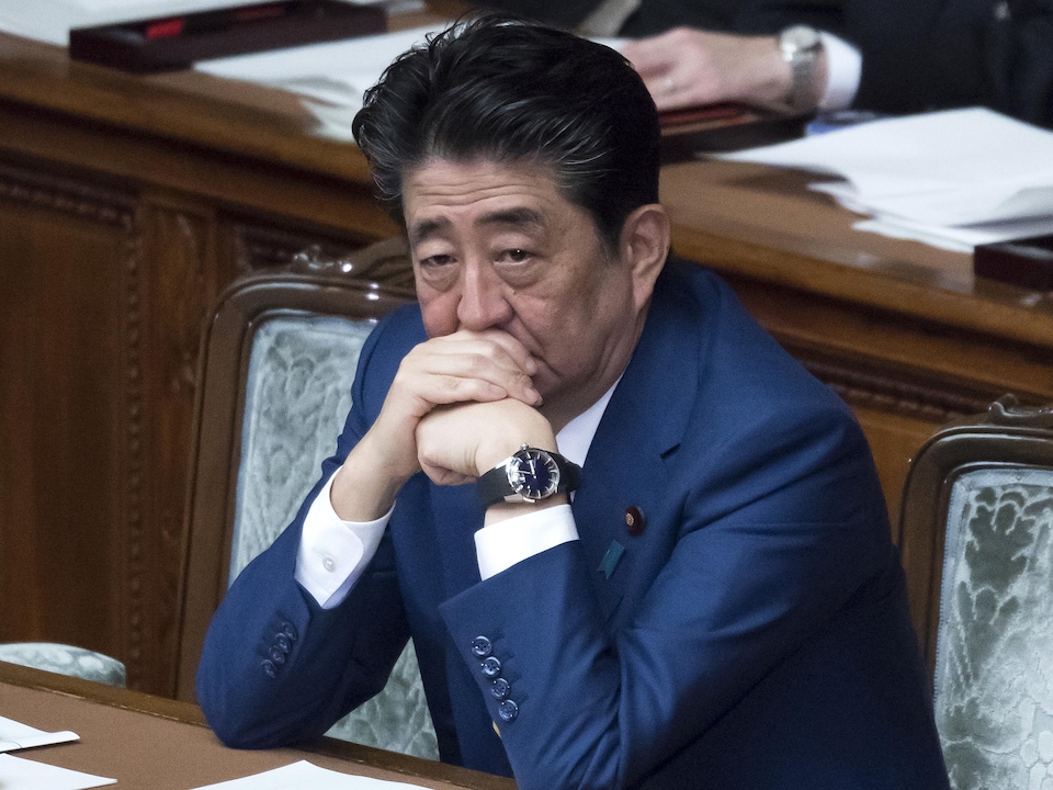 Shinzo Abe s'appuie le visage sur les mains.