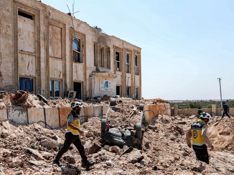 Des Syriens marchent dans les ruines d'un bâtiment.