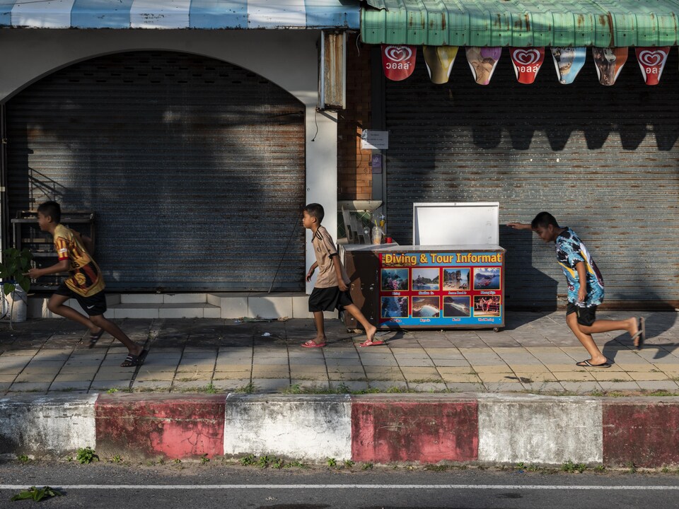Des enfants courent devant des boutiques fermées de Karon Beach, à Phuket, le 17 janvier 2021.