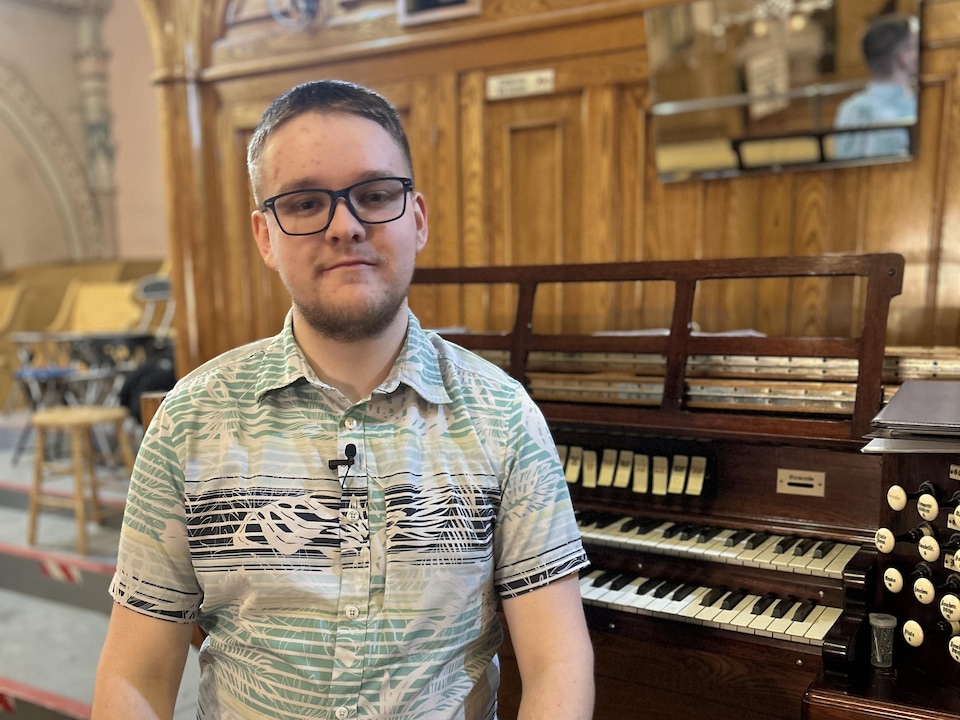 Thomas Fortin, assit près d'un orgue Casavant.