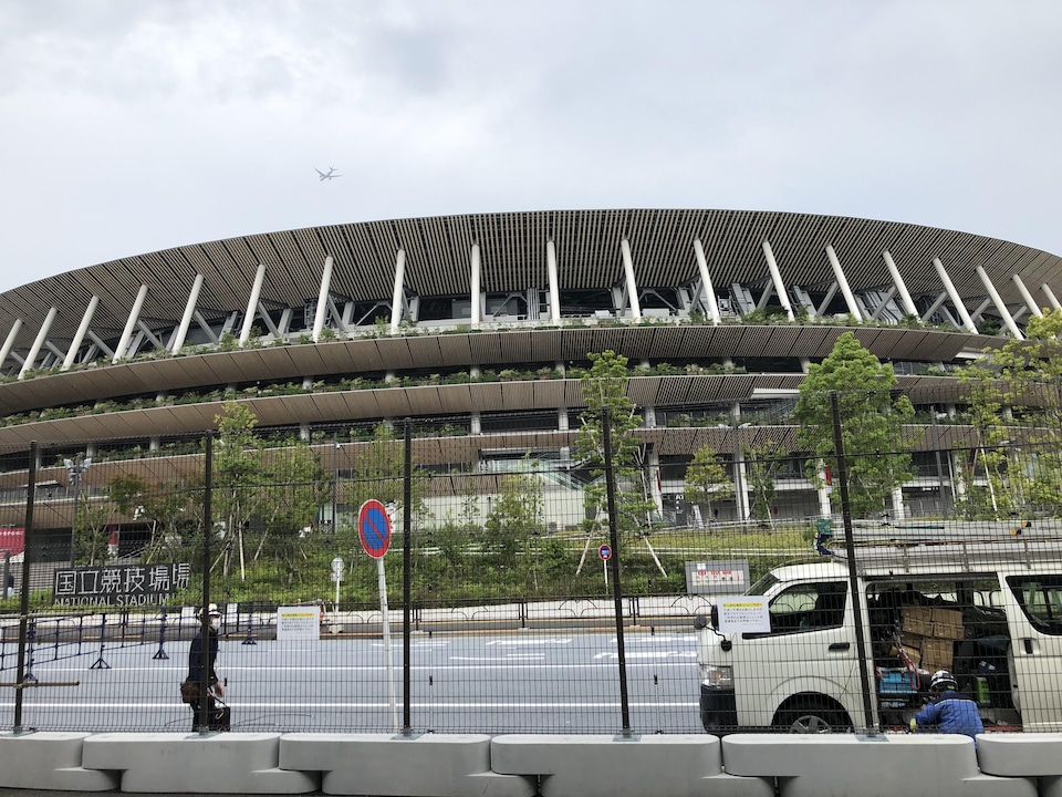 Une clôture noire sur des blocs de béton se dresse devant le stade.