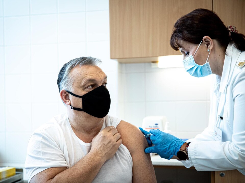 Un homme masqué se fait injecter le vaccin dans le bras.