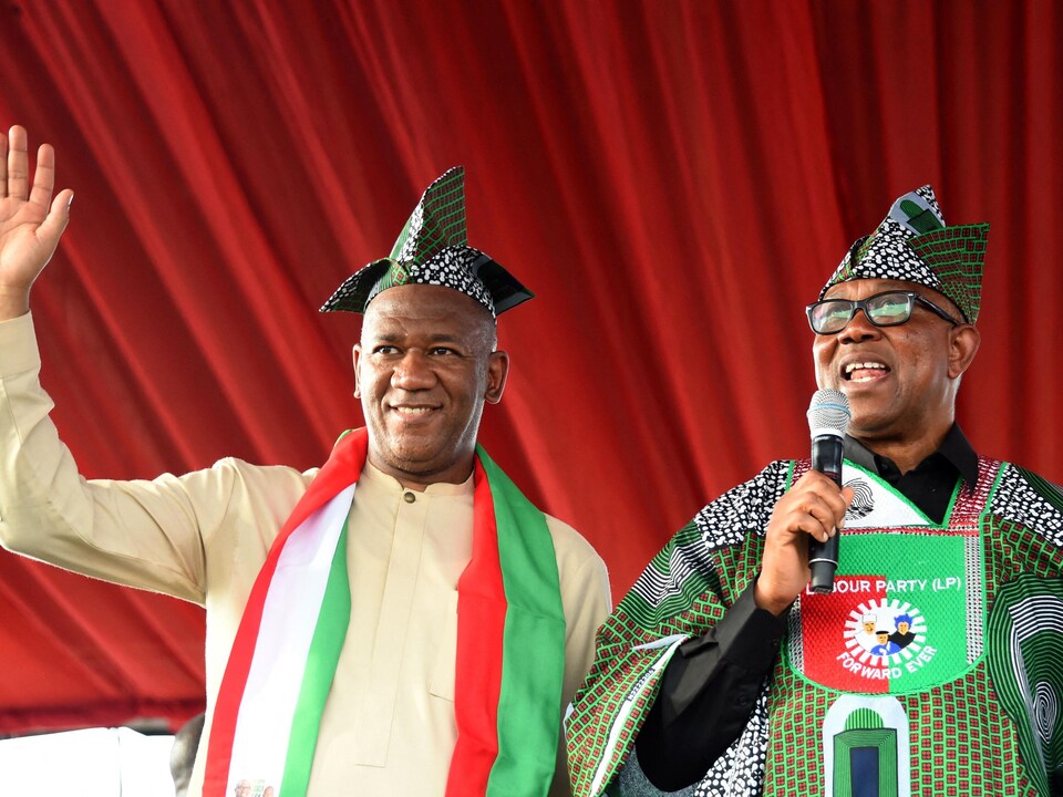 Les deux hommes portent les couleurs du Nigeria (blanc, vert et rouge) et un chapeau traditionnel.