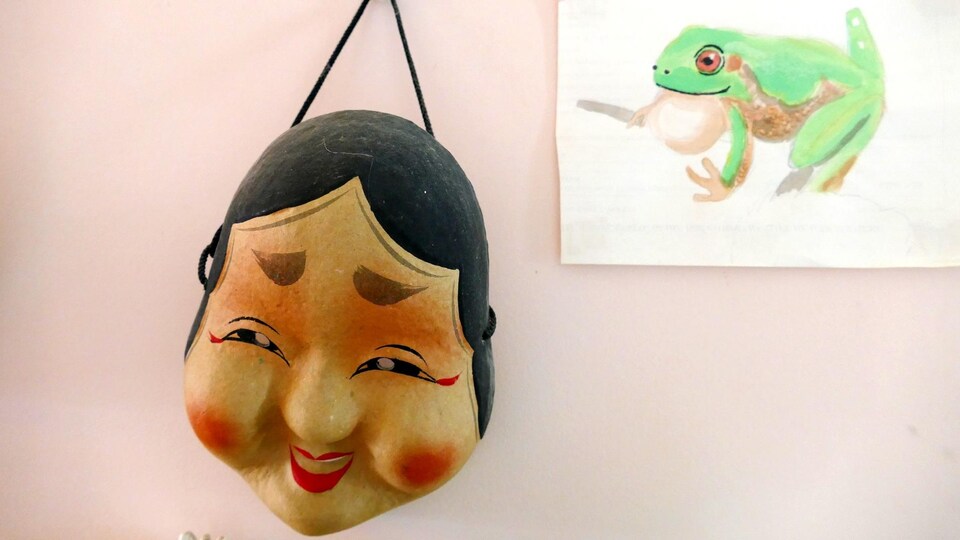 Masque japonais et dessin de grenouille accrochés au mur.