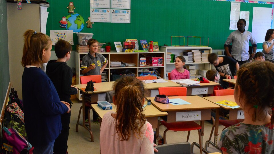 Des enfants jouent avec une balle dans une salle de classe.