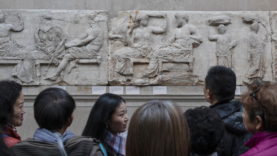 Des gens regardent des sculptures de marbre dans un musée.
