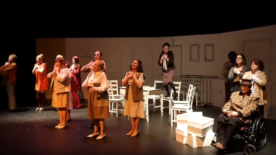Des femmes récitent un texte de pièce de théâtre sur une scène. 