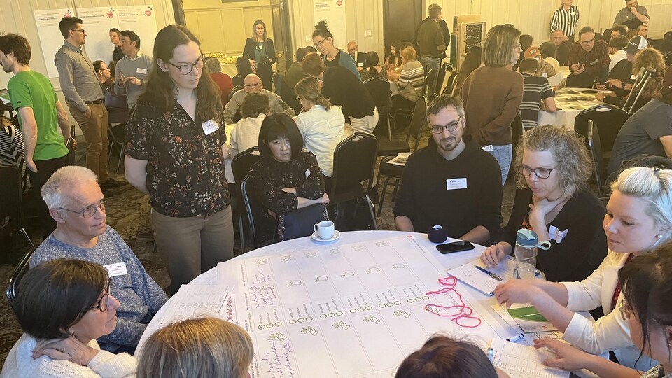 Des participants au forum citoyen Ma Voix Ma Ville discutant autour d'une table.