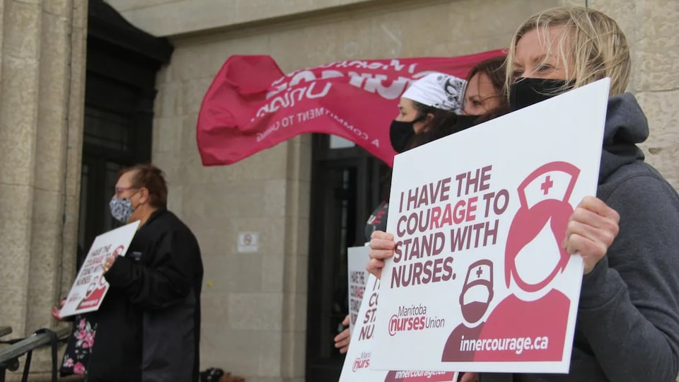 Des personnes manifestent pour les infirmières du Manitoba. 