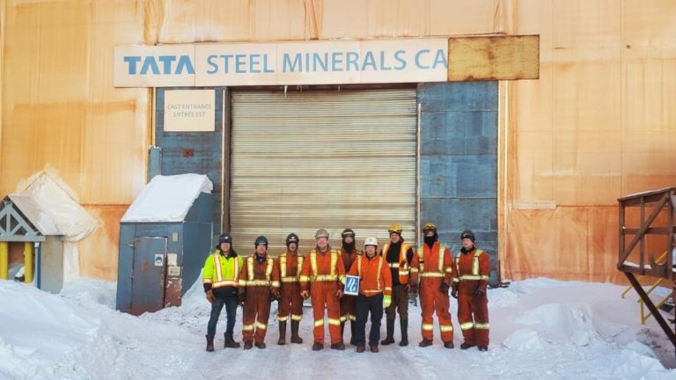 Une dizaine de personnes sont devant des installations minières durant l'hiver. 