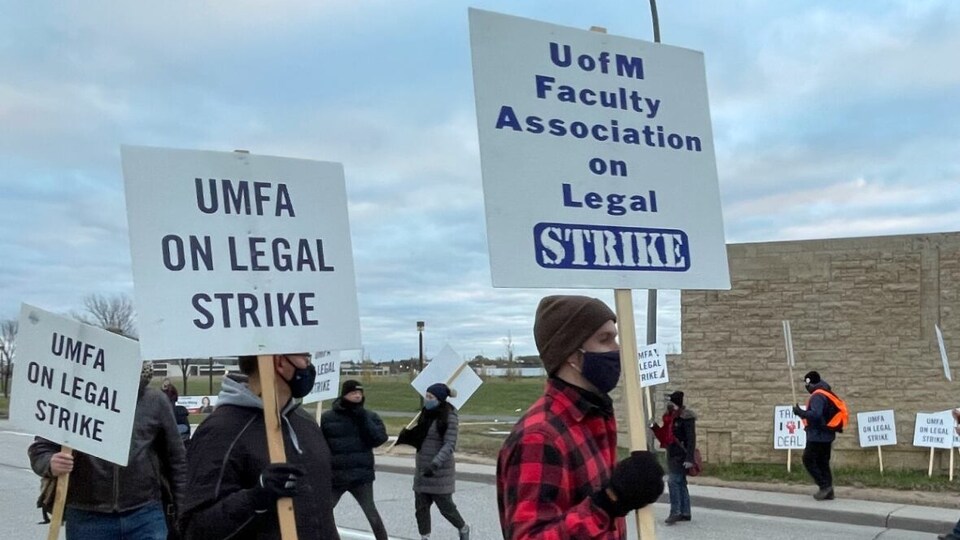 Des membres du syndicats des professeurs de l’Université du Manitoba manifestent à l'extérieur.