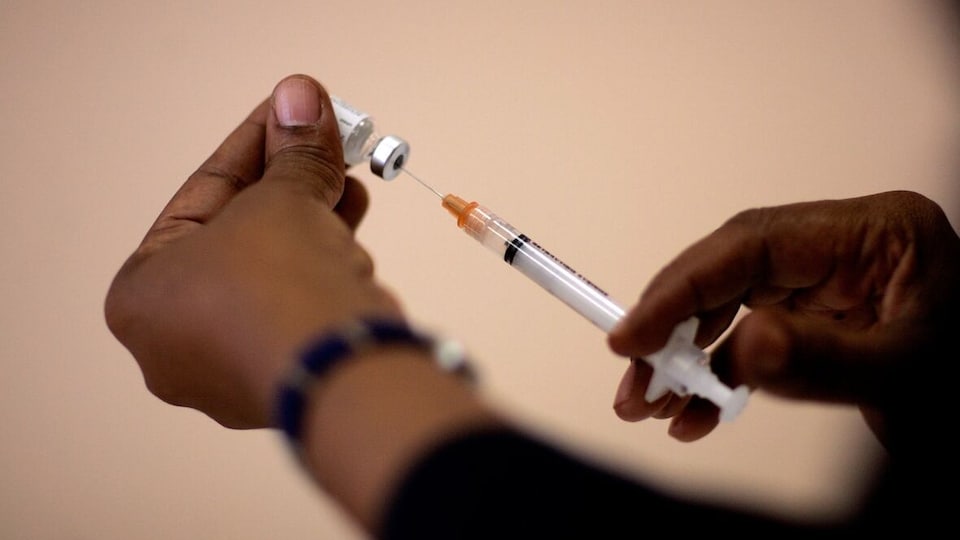 Une personne prépare une dose de vaccin.