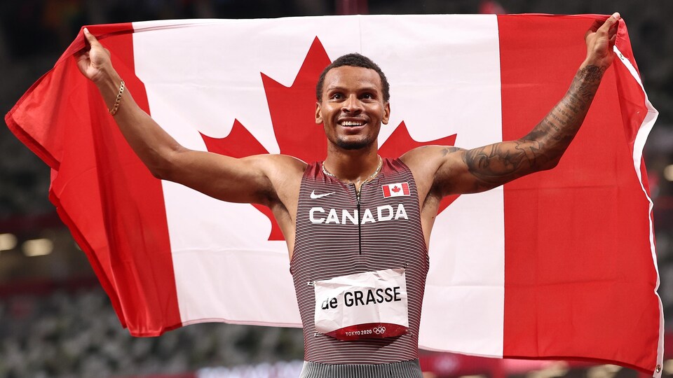 Andre De Grasse fait flotter le drapeau canadien derrière lui.
