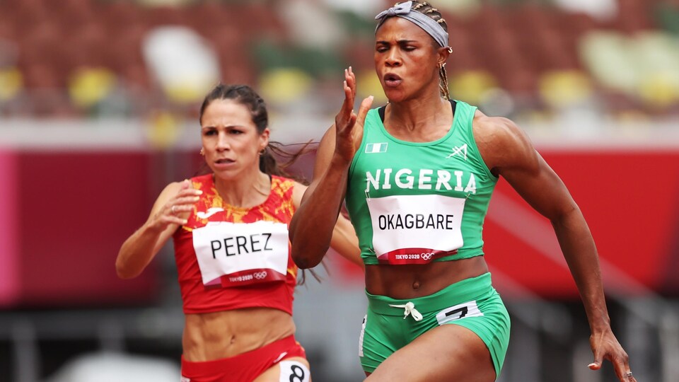 La sprinteuse court, les yeux fermés, bien concentrée pendant un 100 mètres. Elle porte un maillot vert et devance son adversaire espagnole, en rouge.