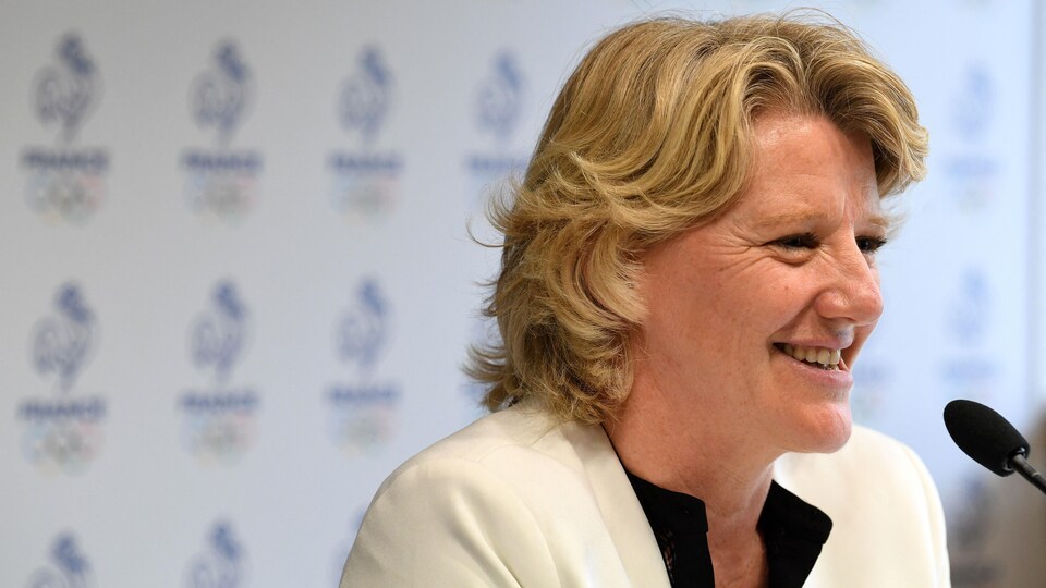 Elle sourit devant un micro lors d'une conférence de presse.