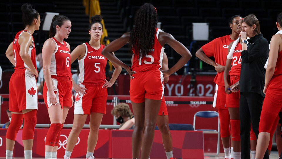 Elles se tiennent debout pendant que leur entraîneuse leur parle.