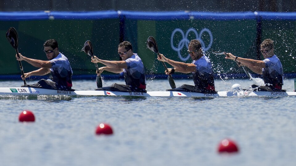Quatre athlètes masculins pagaient ensemble dans un kayak.