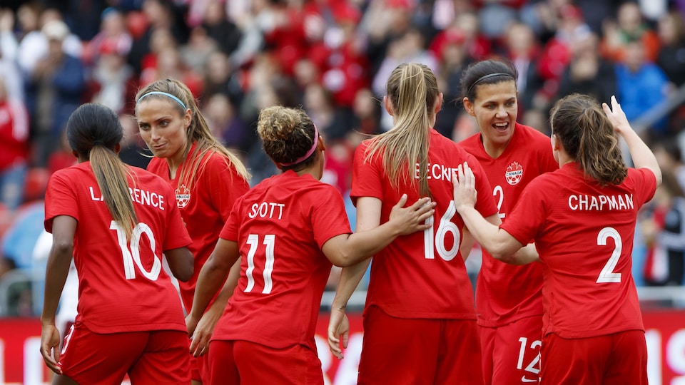 Christine Sinclair célèbre un but sur le terrain avec des coéquipières de l'équipe féminine canadienne de soccer.