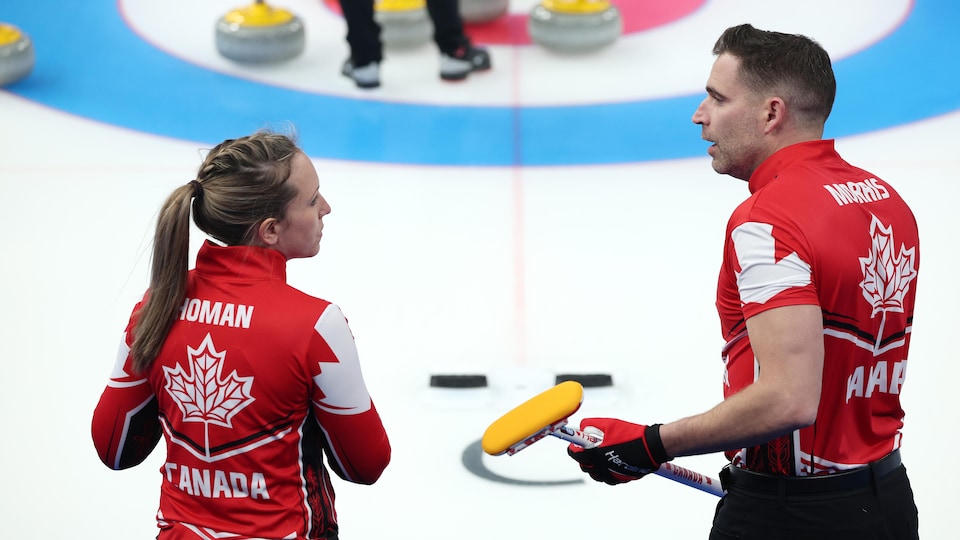 Rachel Homan e John Morris discutino sulle piste di curling. 