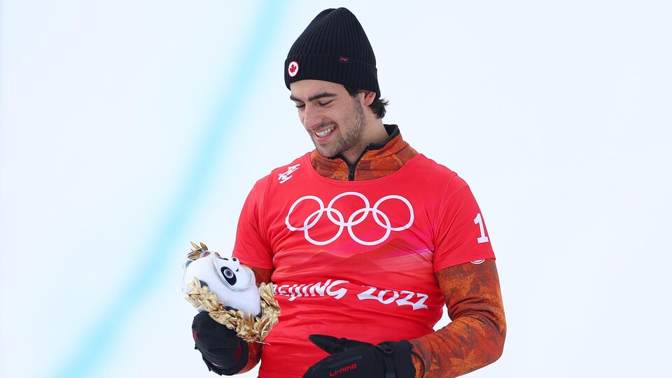 Eliot Grondin célèbre sa performance sur le podium après avoir remporté la médaille d'argent en snowboard cross en surf des neiges aux Jeux de Pékin.