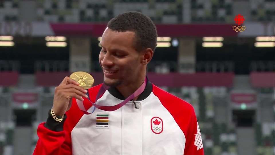 Andre De Grasse sur le podium regarde sa médaille d'or.