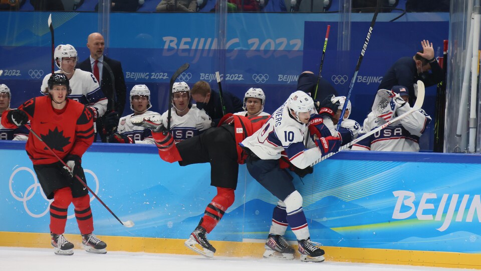 Un joueur de hockey se fait plaquer près du banc de ses adversaires.