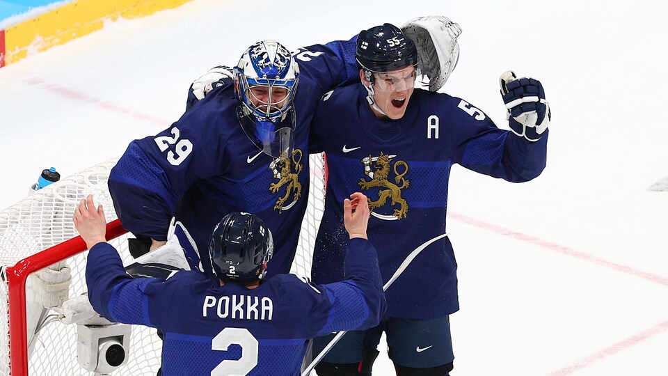 Le gardien finlandais et deux coéquipiers célèbrent la victoire devant le filet.
