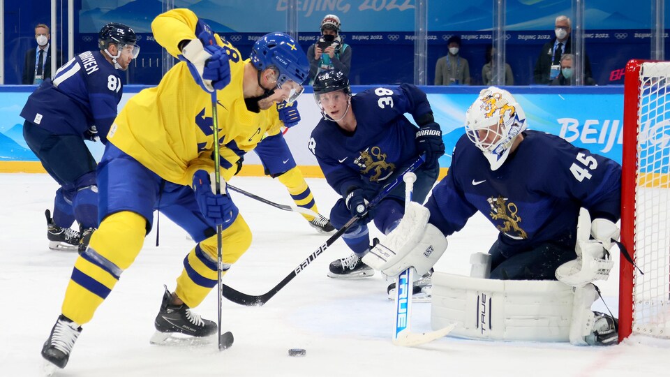 Le joueur suédois tente un tir contre le gardien finlandais. 