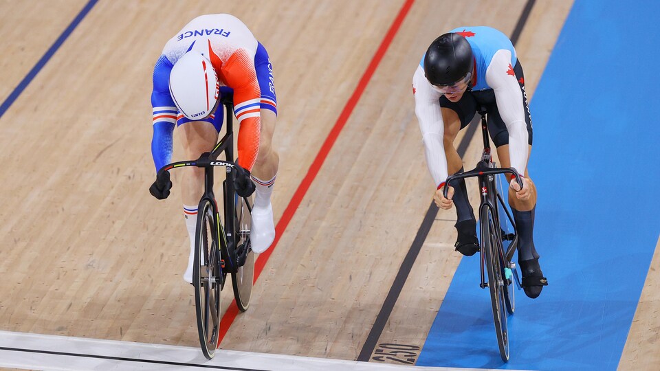 Deux cyclistes sur piste croisent la ligne d'arrivée.