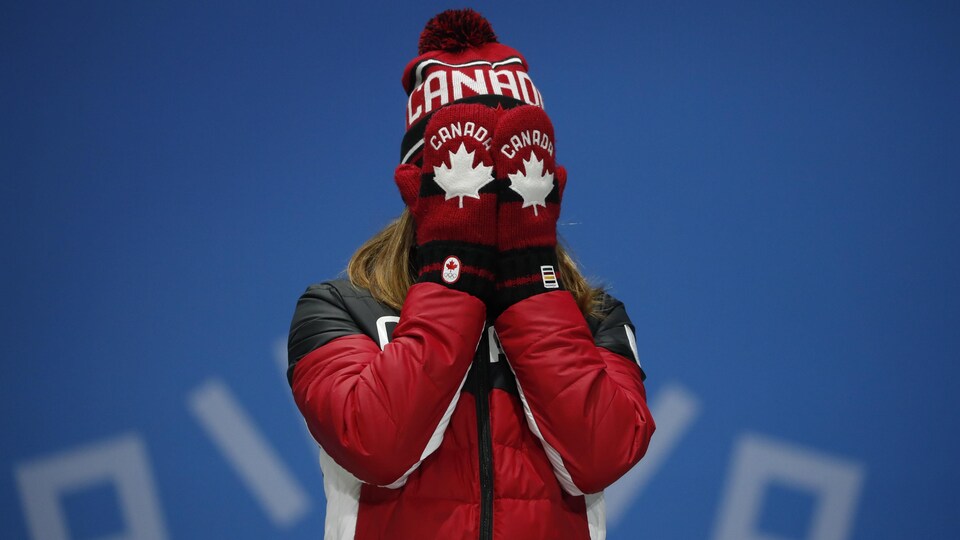 Une athlète canadienne place ses deux mains sur son visage.
