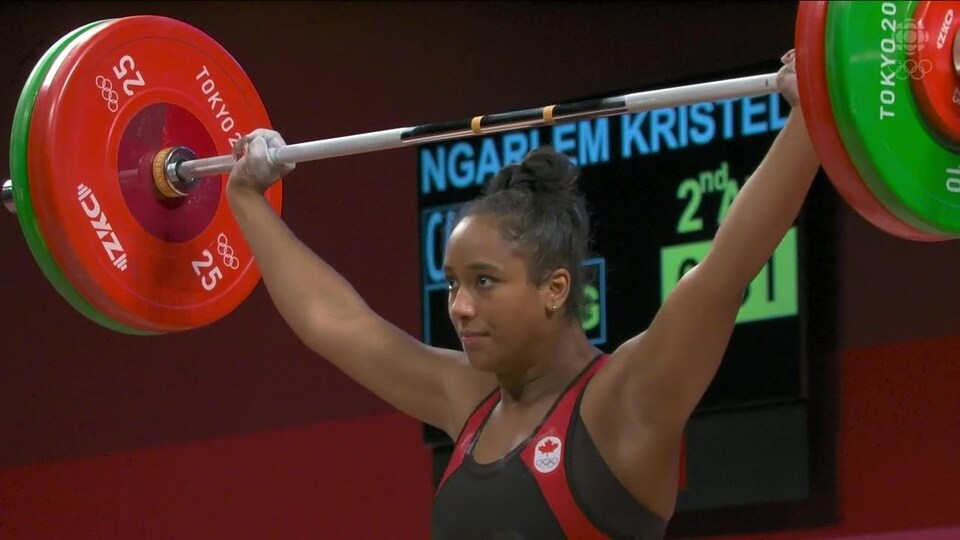 Concentrée, la Canadienne tient la barre avec ses deux bras au-dessus de sa tête.