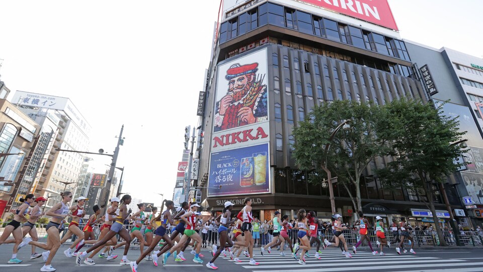 Des dizaines de marathoniennes courent dans un centre-ville.